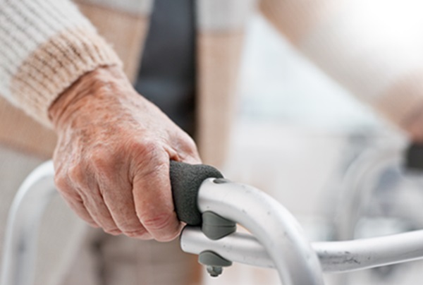 Close-up of an elderly person's hand firmly gripping the handle of a metal walker in an Alabama nursing home.